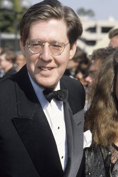 a man in a tuxedo standing next to a woman