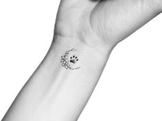 a person's wrist with a small dog paw tattoo on the left side of their arm