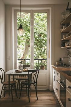 a small table and chairs in front of a window with open shelves on both sides