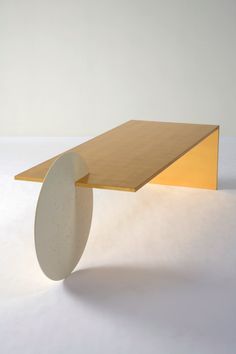 a wooden table with a white circle on the top and yellow base, against a white background