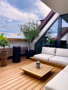 a wooden deck with white couches and coffee table on the other side of it