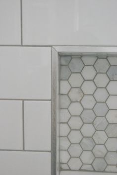 the corner of a bathroom with white tile and hexagonal pattern on it's walls