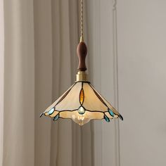 a stained glass lamp hanging from a ceiling in a room with white walls and curtains