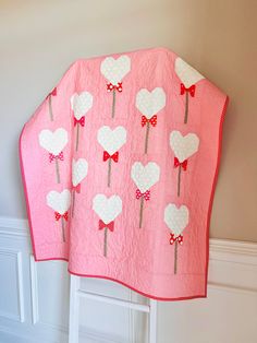 a pink blanket with hearts and bows on it hanging from the wall next to a white door