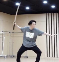 a man holding a baseball bat while standing on top of a hard wood floor in an empty room