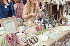 a woman standing next to a table filled with items