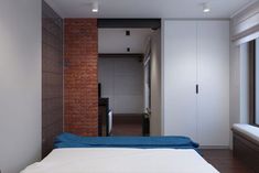 there is a bed in the room with blue sheets on it and a brick wall