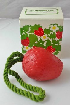 a red ball tied up to a green rope next to a box of strawberry hair