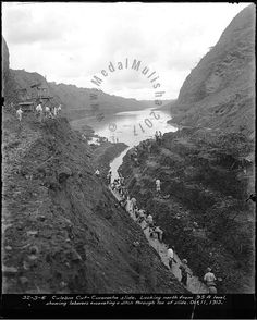 an old black and white photo of people walking on the side of a hill next to a body of water