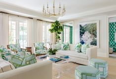 a living room filled with lots of white furniture and green pillows on top of them