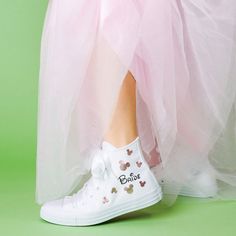 a close up of a person's feet wearing white shoes with pink tulle