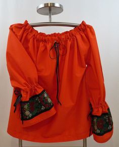 This blouse is a size US 12-14 and will comfortably fit a bust and hip measurement of up to 38 inches (96.52cm).   It is made from a gorgeous red cotton voile and features a band of 100mm wide traditional Czech/Slovak folk ribbon on each sleeve.   It's perfect for your special Slavic community even.  But this blouse is so elegant and versatile, it will look just as nice with a pair of jeans or a skirt.   Take a chance and be different!    The cut is an excellent example of a simple, graceful gar Peasant Style Cotton Blouse With Yoke, Peasant Style Cotton Blouse With Yoke Detail, Red Peasant Blouse For Spring, Spring Red Peasant Blouse, Red Folk Blouse For Fall, Fall Cotton Peasant Top With Smock Detail, Fall Cotton Smock Peasant Top, Fall Cotton Smocked Peasant Top, Red Cotton Folk Top