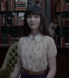 a young woman standing in front of a bookshelf