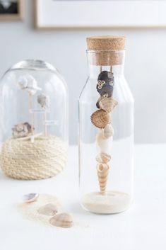 two glass bottles filled with sand and shells