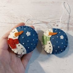 two handmade snowman ornaments hanging from strings