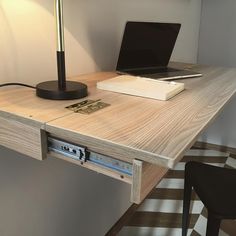 a laptop computer sitting on top of a wooden desk next to a lamp and chair