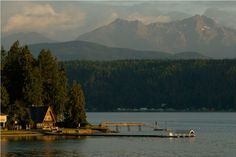 a house on the water with mountains in the background