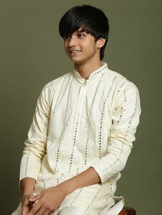 Yuva By VASTRAMAY Boys Cream Embroidered Mirror Work Kurta Pyjama Set This cream colored kurta pyjama set features beautiful vertical mirror embroidery, adding a touch of elegance and sophistication. The kurta has a straight cut, mandarin collar, and two pockets with mirror work detail. The set is made from poly georgette fabric for a comfortable feel. Key Features Cream colored with vertical mirror embroidery Straight kurta with mandarin collar Two pockets with mirror work detail Cream colored Cream Cotton Traditional Wear With Long Sleeves, Long Sleeve Cotton Traditional Wear With Mirror Work, Cotton Long Sleeve Tops With Zari Work, Cream Long Sleeve Cotton Traditional Wear, Cream Cotton Kurta For Diwali, Traditional Self-design Tops For Eid, Long Sleeve Tops With Chikankari Embroidery For Diwali, Diwali Long Sleeve Tops With Chikankari Embroidery, Long Sleeve Cotton Tops With Zari Work