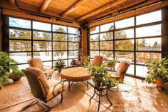 a living room filled with furniture and lots of windows covered in snow next to potted plants