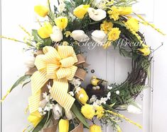 a wreath with yellow and white flowers on the front door