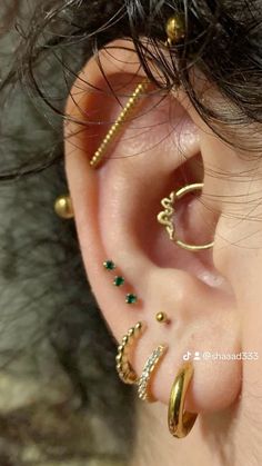 an ear with three different types of piercings on it's sides and one is gold