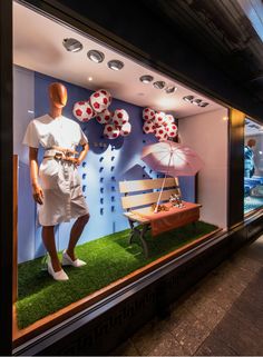 a mannequin in a window display with umbrellas