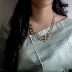 a woman wearing a necklace with pearls on it