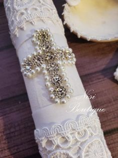 a white wedding garter with pearls and lace on it, next to seashells