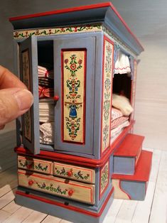 a hand is pointing at a miniature cabinet