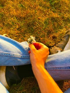 a person sitting on the grass holding a flower