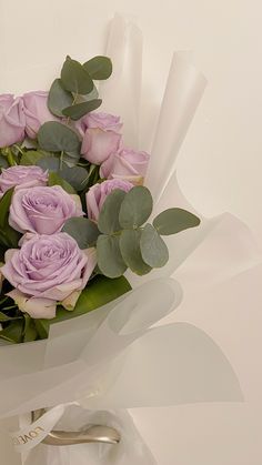 a bouquet of purple roses and eucalyptus leaves