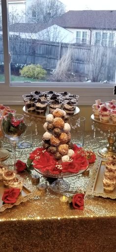 a table topped with lots of desserts next to a window