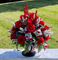 a vase filled with red flowers on top of a white tablecloth covered bench in the grass