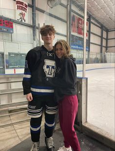 a man and woman standing next to each other in front of an ice rink