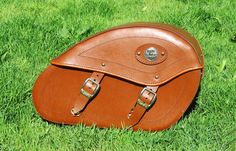 a brown leather bag sitting on top of green grass