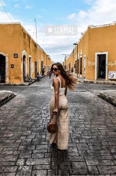 a woman standing in the middle of an alley way with her hair blowing in the wind