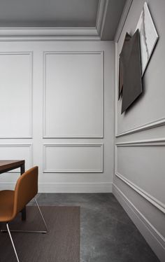 an empty room with two chairs and a table in front of white paneled walls