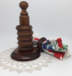 a wooden object sitting on top of a doily next to a piece of cloth