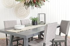 a dining room table with chairs and plates on it in front of a wall decoration