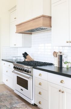 a stove top oven sitting inside of a kitchen next to white cabinets and counter tops