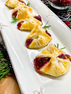 small pastries are on a white plate with cranberry sauce and sprigs