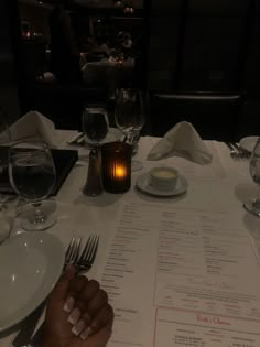 a person sitting at a table with a menu in front of them and wine glasses on the table