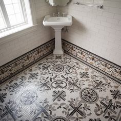 a white sink sitting under a bathroom mirror next to a tiled floor with crosses on it