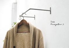 a coat hanging on a clothes hanger next to a white wall