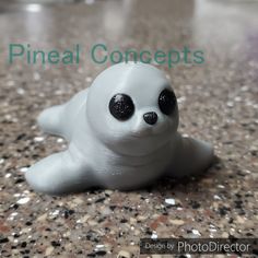 a small white toy with black eyes and a seal on it's back sitting on a table