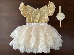 This baby girl vintage style, French Ivory and Gold Sequins party set is gorgeous. The French Ivory Fluffy Layered Skirt is super soft and fluffy. For your baby's comfort, it is made using soft fabric and lace in a beautiful French Ivory color that is perfect for the summer. The elastic waistband allows for full comfort. The chic baby gold sequins romper completes the style. It is made with shiny gold sequins and fully lined with a soft cotton fabric. The flutter sleeves make it girly and sophis Fitted Cream Sets With Ruffles, Cream Fitted Ruffle Sets, Cream Fitted Ruffled Sets, Cream Fitted Sets With Ruffles, White Ruffled Sets For Dress-up Occasions, White Ruffled Sets For Dress-up, White Ruffled Dress-up Sets, White Ruffle Dress-up Sets, Sequins Romper