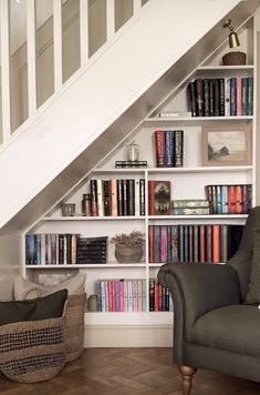 a chair sitting in front of a bookshelf filled with lots of books next to a stair case