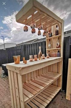 an outdoor bar made out of pallet wood with hanging lights and bottles on it