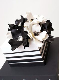 a black and white flower arrangement on top of a cake that looks like it has been made out of fondant