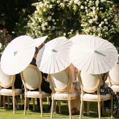 several people sitting in chairs with umbrellas over their heads and feet on the lawn